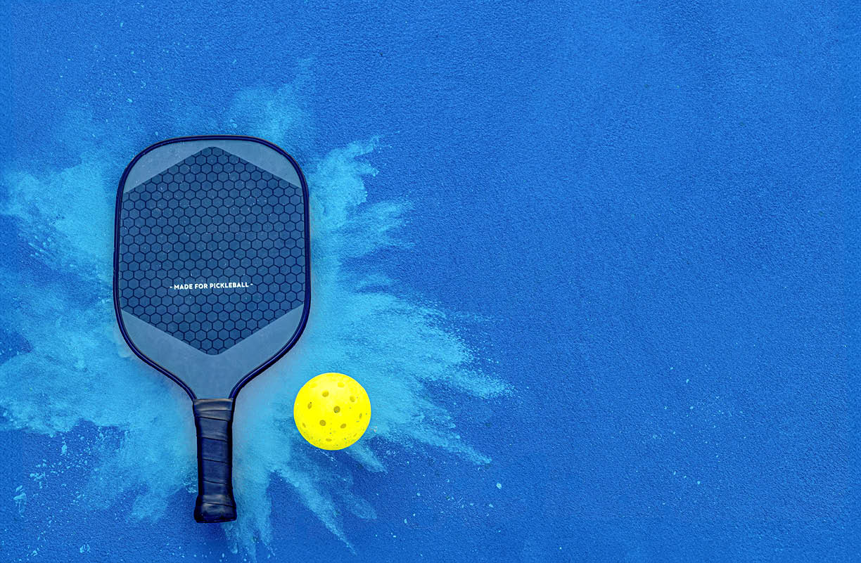 Pickleball tennis racket on the court. Blue background with copy space. Sport court and ball.